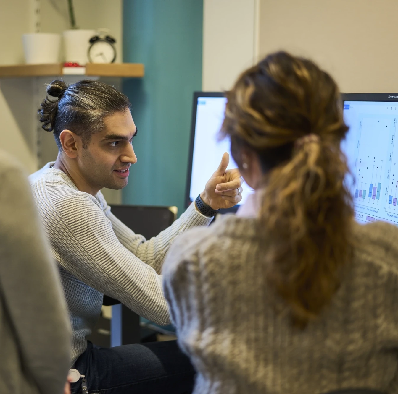 Photo of two researchers discussing findings in front of a computer screen
