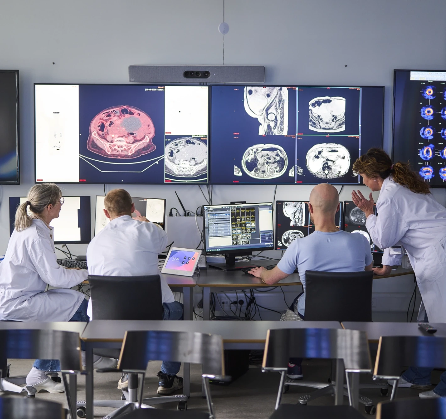 Photo of four researchers in front of several large screens discussing scans