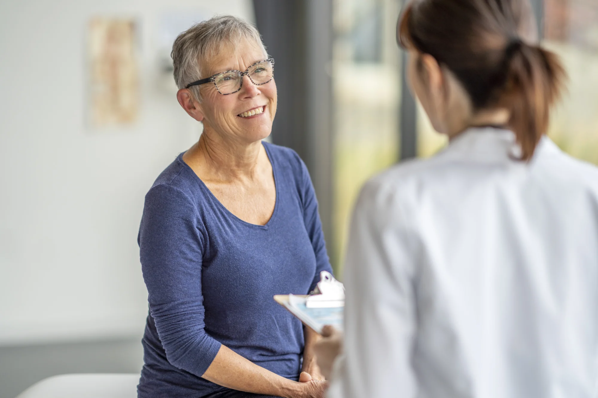 Photo of a nurse talking to a woman wearing glasses